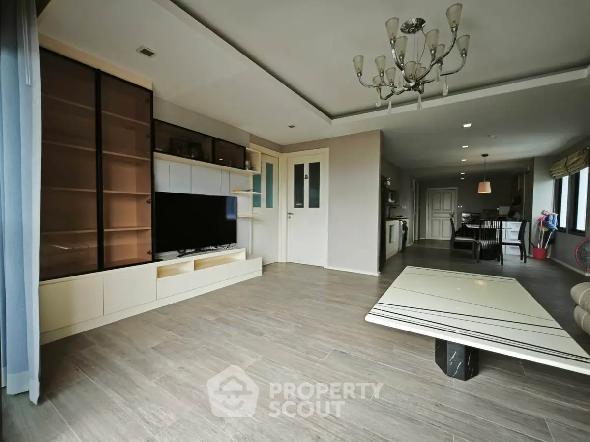 Spacious modern living room with elegant chandelier and open layout, perfect for family gatherings.