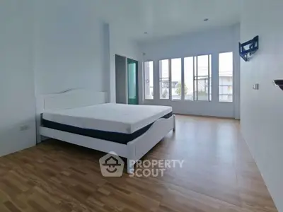 Spacious bedroom with large windows and wooden flooring in modern apartment