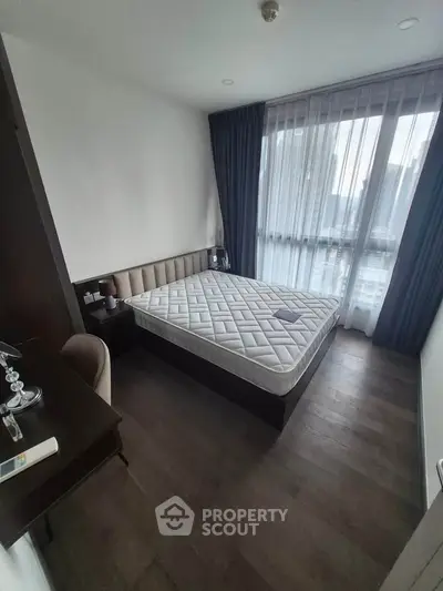 Modern bedroom with large window and stylish furnishings in a contemporary apartment.