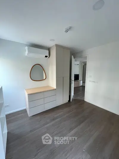 Modern bedroom with sleek flooring and built-in storage, featuring air conditioning and minimalist design.