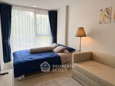 Cozy bedroom with modern decor, featuring a comfortable bed, stylish lamp, and large window with curtains.