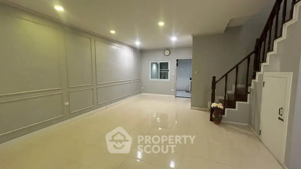 Spacious modern living room with elegant staircase and polished tile flooring