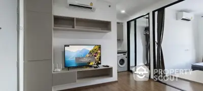 Modern living room with TV, air conditioning, and washing machine in open layout apartment.