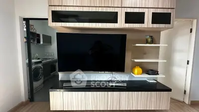 Modern living room with sleek TV unit and adjacent laundry area featuring washer and dryer.
