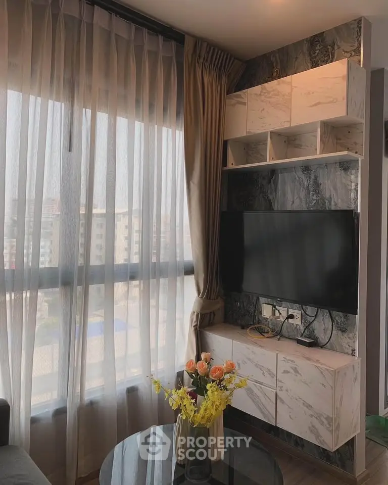 Modern living room with large window, stylish TV unit, and elegant decor