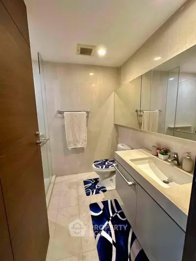 Modern bathroom with sleek fixtures and stylish decor, featuring a spacious shower and elegant vanity.