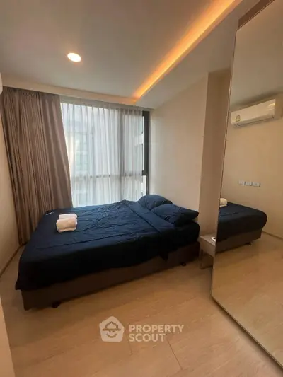 Modern bedroom with large window and stylish lighting, featuring a comfortable bed and sleek decor.