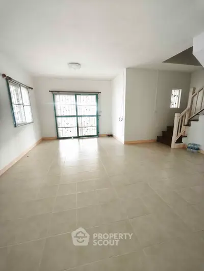 Spacious unfurnished living room with large windows and tiled flooring, perfect for customization.