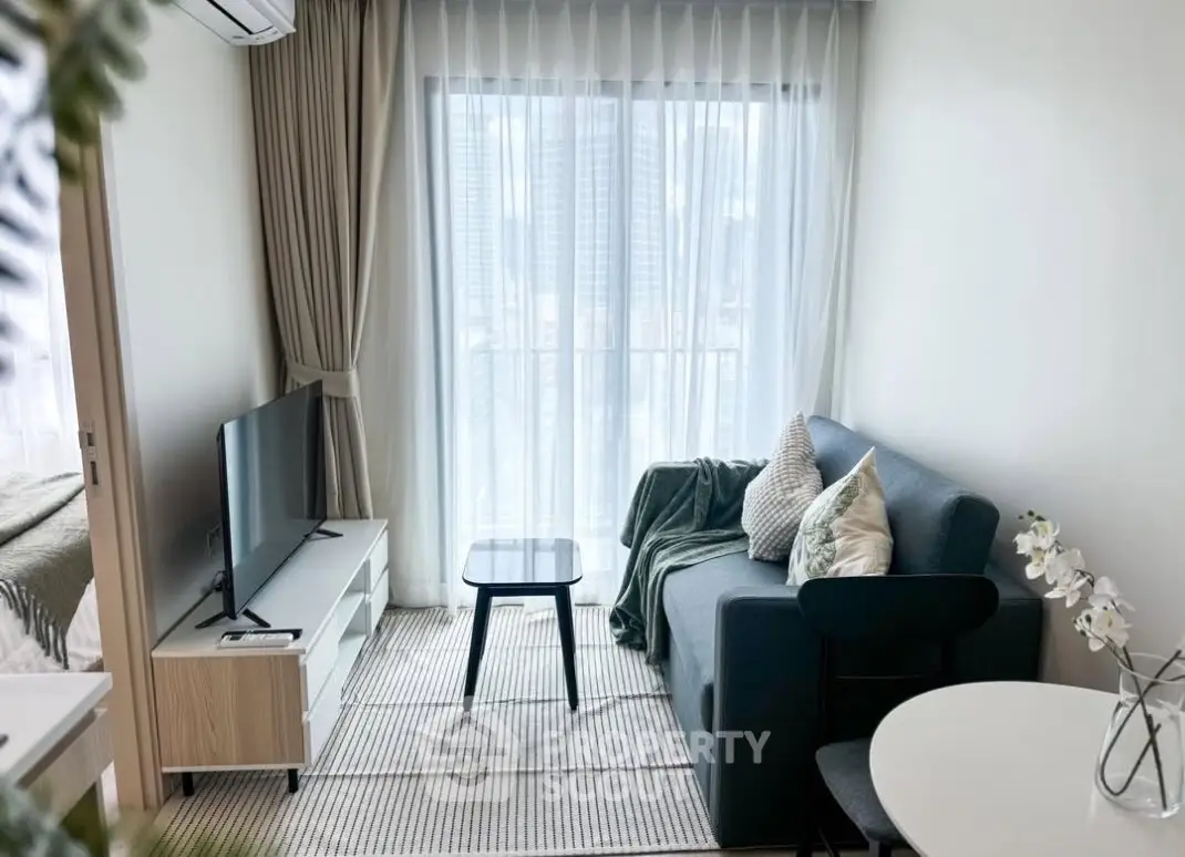 Modern living room with sleek furniture and city view through large windows.