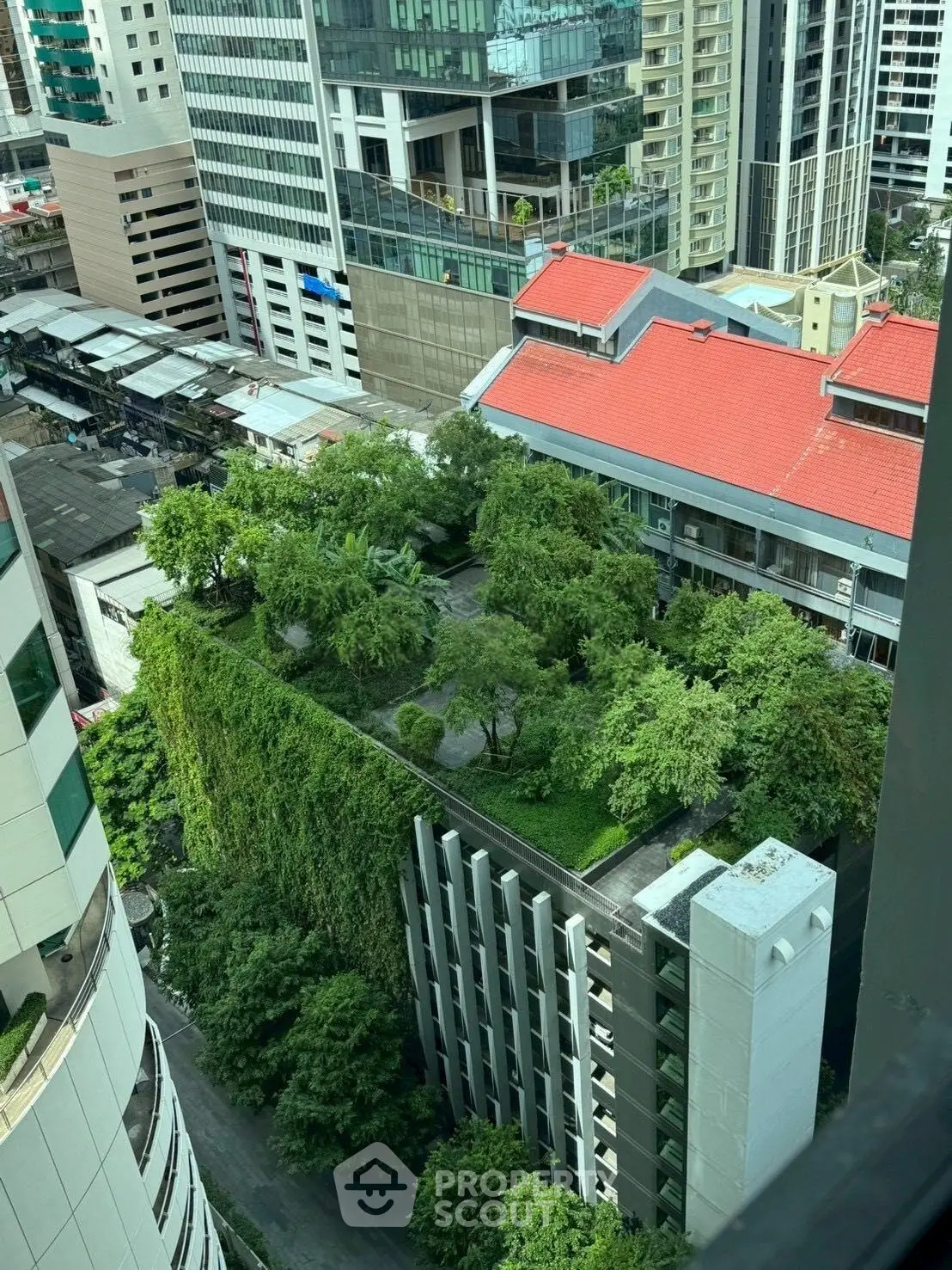 Stunning aerial view of urban building with lush green rooftop garden in vibrant cityscape.