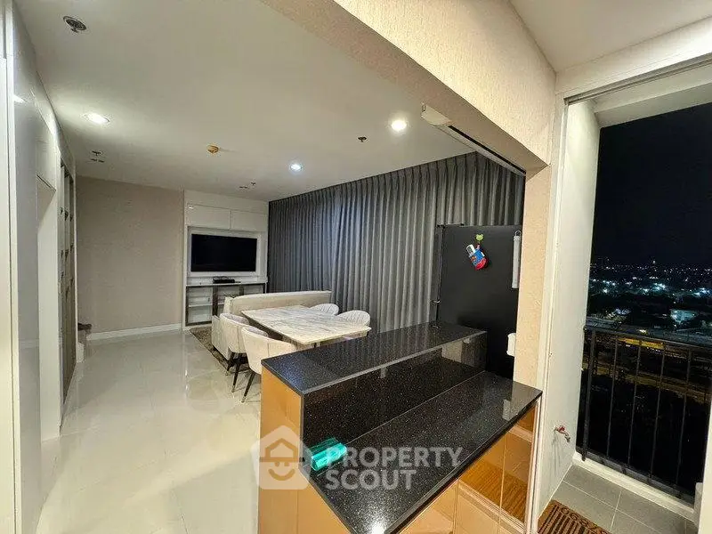 Modern open-layout living room with city view balcony, sleek kitchen counter, and cozy dining area.