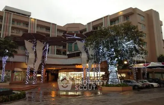 Modern building exterior with festive lighting and trees, showcasing a vibrant urban lifestyle.