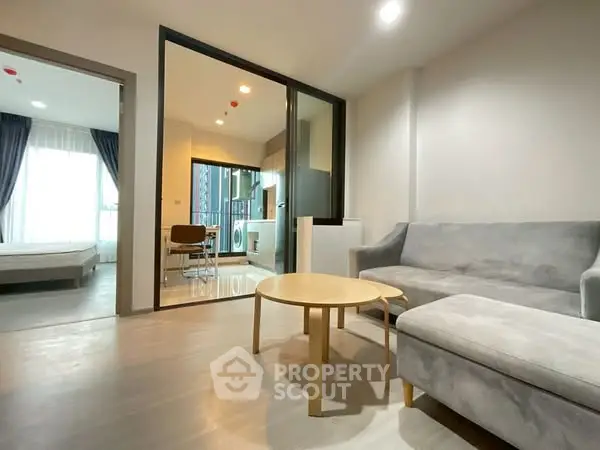 Modern living room with open layout and natural light, featuring a cozy sofa and dining area.