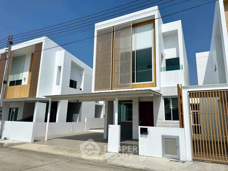 Modern two-story house with sleek design and large windows in a suburban neighborhood.