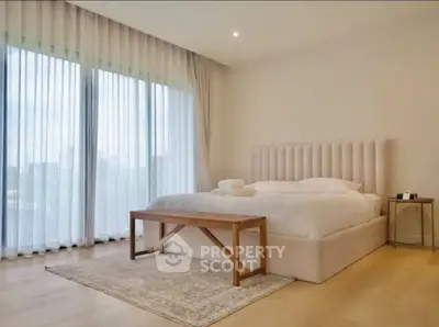 Luxurious bedroom with elegant decor and large windows offering natural light.