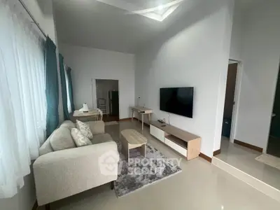 Modern living room with cozy sofa, wall-mounted TV, and natural light from large windows.