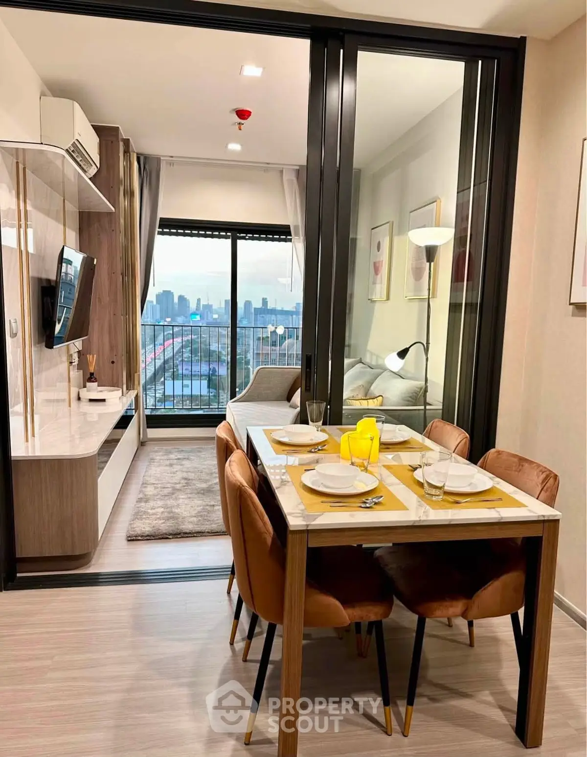Modern open-plan living and dining area with city view, featuring stylish furniture and elegant decor.