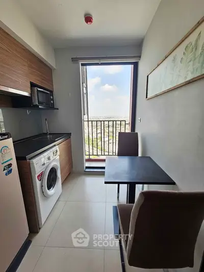 Modern kitchen with balcony view, featuring washing machine and microwave in compact space.