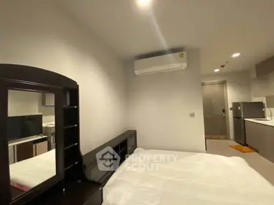 Modern bedroom with sleek furniture and compact kitchen area, ideal for urban living.