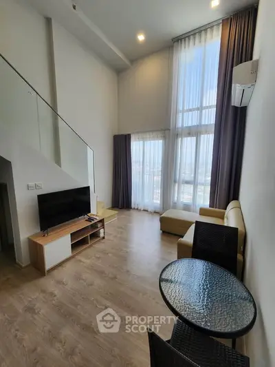 Spacious modern living room with high ceilings and large windows offering stunning city views.