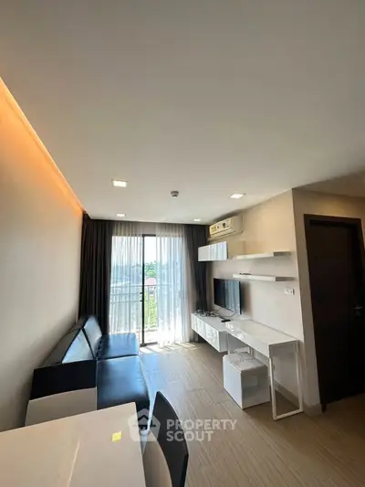 Modern living room with sleek furniture and large window offering natural light and city view.