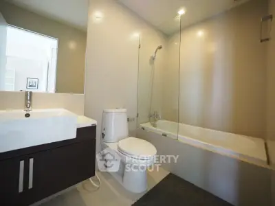 Modern bathroom with sleek fixtures and glass-enclosed bathtub in contemporary home.