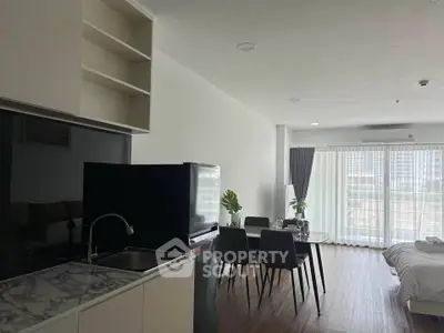 Modern open-plan apartment with kitchen, dining area, and large windows for natural light.