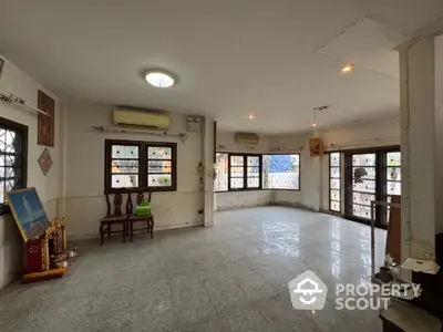 Spacious living room with large windows and marble flooring in a well-lit home.