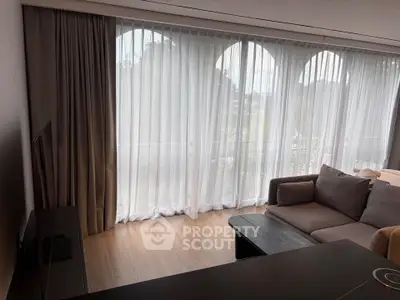 Spacious living room with large windows and modern furniture, offering abundant natural light and a cozy atmosphere.
