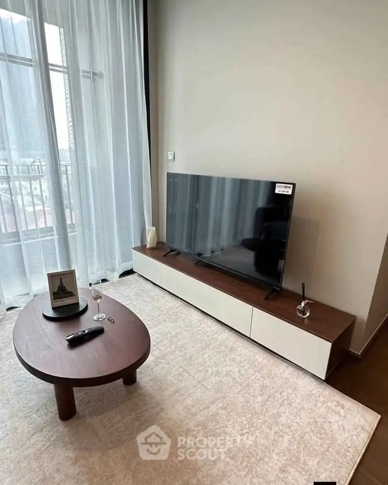 Modern living room with sleek TV setup and elegant coffee table, featuring floor-to-ceiling windows.