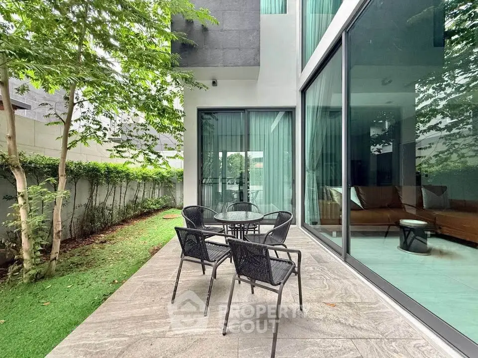 Modern patio with glass doors and garden view, perfect for outdoor relaxation and entertainment.