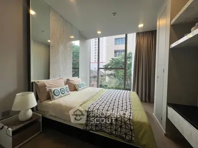 Modern bedroom with large window and stylish decor in urban apartment.