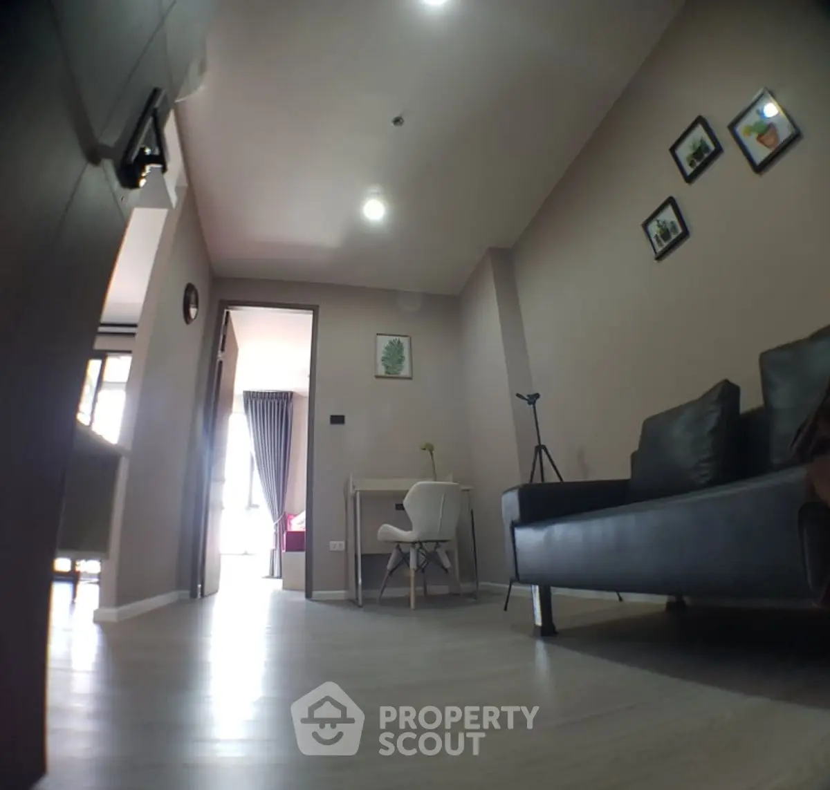 Modern living room with sleek sofa and study area, featuring stylish decor and natural light.