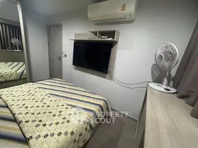 Cozy bedroom with air conditioning and wall-mounted TV, featuring modern decor and striped bedding.