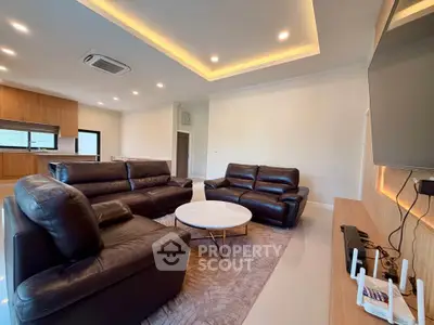 Spacious modern living room with leather sofas and open kitchen layout