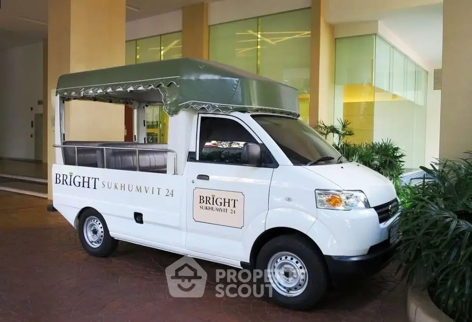 Modern building entrance with branded shuttle van at Bright Sukhumvit 24, offering convenient urban living.