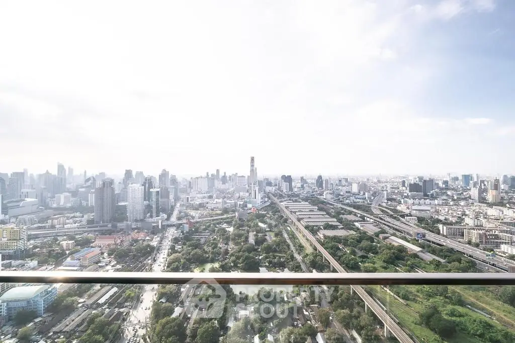 Stunning panoramic city view from high-rise balcony, showcasing urban skyline and lush greenery.