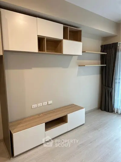 Modern living room with built-in wooden shelves and cabinets, featuring sleek design and natural light.