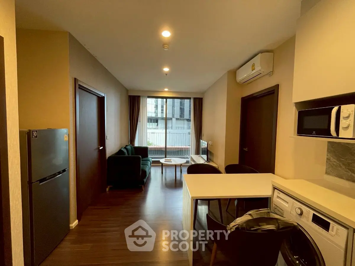 Modern apartment interior with open layout, featuring kitchen and living area, wooden flooring, and natural light.
