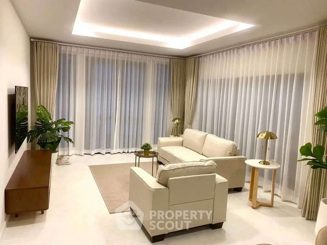 Elegant living room with modern furniture and large windows, featuring stylish lighting and lush indoor plants.