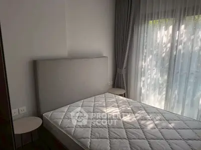 Modern bedroom with large window and elegant curtains, featuring a comfortable bed and stylish side tables.