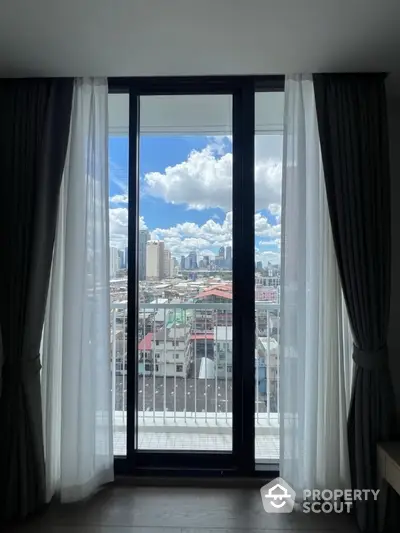 Stunning city view from modern apartment balcony with floor-to-ceiling windows and elegant curtains.