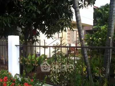 Charming garden view of a cozy home with lush greenery and elegant iron fencing.