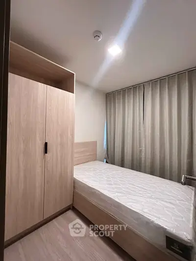 Cozy bedroom with single bed and wooden wardrobe, perfect for minimalist living.