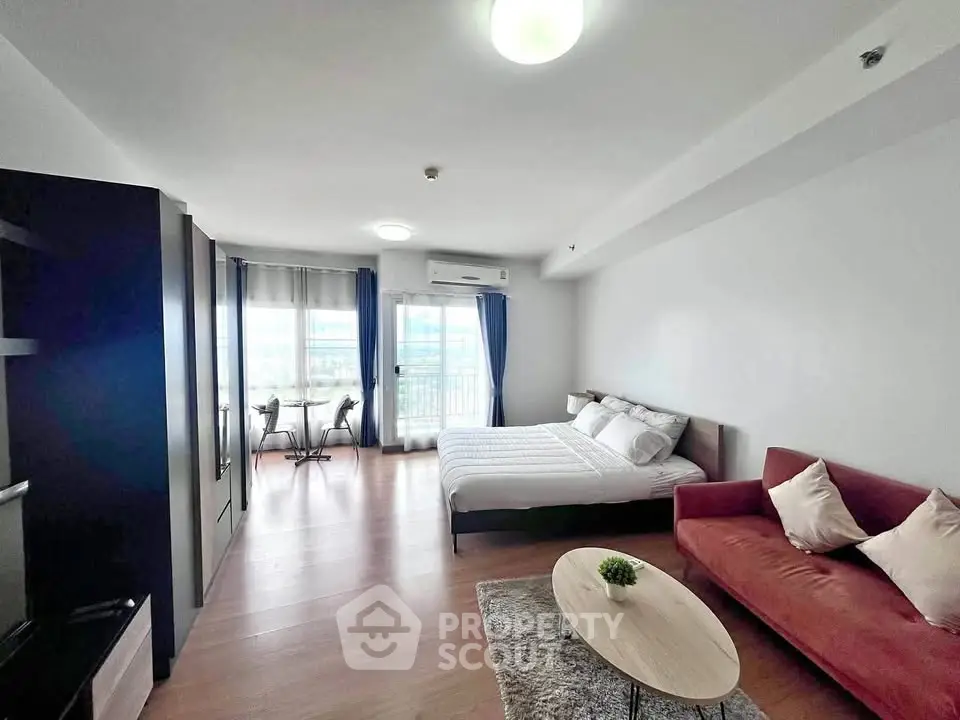 Spacious modern studio apartment with cozy living area and large windows.
