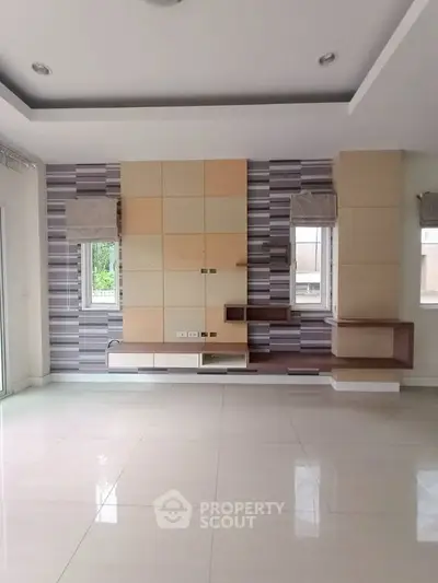 Spacious modern living room with stylish wall paneling and large windows for natural light.