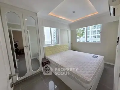 Modern bedroom with large windows and mirrored wardrobe in high-rise apartment.