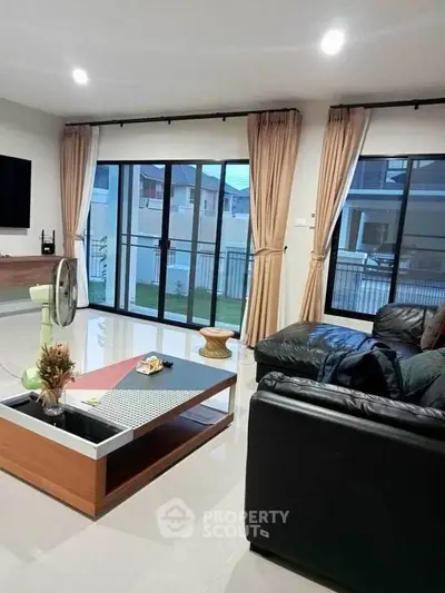 Spacious living room with modern decor and large windows overlooking a garden.