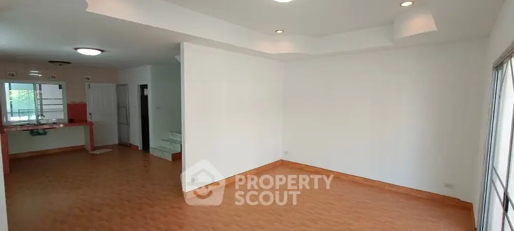 Spacious open-plan living room with wooden flooring and modern kitchen area