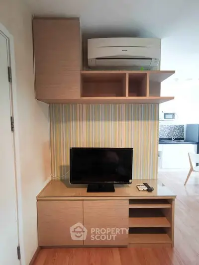 Modern living room with built-in TV cabinet and air conditioning unit, featuring stylish wood flooring.